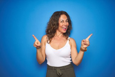 Mavi yalıtılmış arka planda duran kıvırcık saçlı, kendinden emin, farklı yönleri gösteren orta yaşlı bir kadın. Reklam için boşluk kopyala