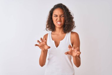 İzole edilmiş beyaz arka planda dikilmiş tişört giyen Brezilyalı genç bir kadın komik bir şekilde kedi gibi pençe hareketi yapıyor, saldırgan ve seksi bir ifade.