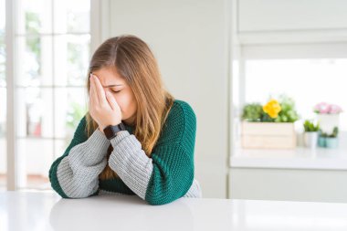 Genç, güzel, iri yarı, sıradan çizgili bir kazak giyen, suratını ellerle örten, ağlayan bir kadın. Depresyon kavramı.