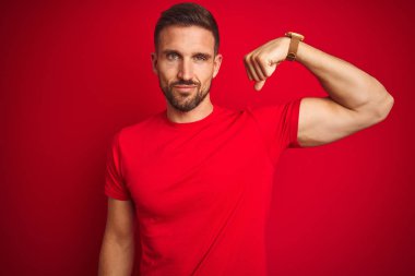 Kırmızı arka plan üzerine gündelik tişört giyen genç yakışıklı güçlü, kendine güvenen ve güçten gurur duyan biri.