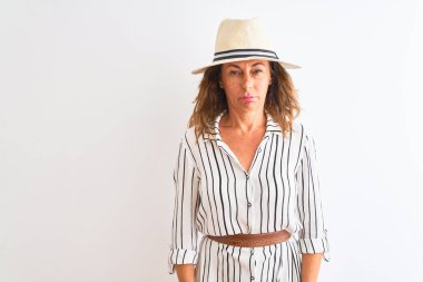 Çizgili elbise ve şapka giyen orta yaşlı iş kadını, izole edilmiş beyaz arka planda depresif ve endişe içinde, sinirli ve korkmuş bir şekilde ağlıyor. Üzücü ifade.