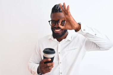 Örgü örgülü Afrikalı Amerikalı iş adamı izole edilmiş beyaz arka planda kahve içiyor, gülümsüyor ve el pençe divan duruyor.