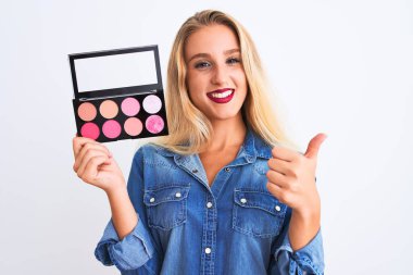 Güzel, sarışın, makyajlı genç bir kadın izole edilmiş beyaz arka planda mutlu bir şekilde duruyor. Gülümsüyor.