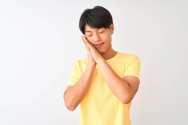 Sarı günlük tişört giyen Çinli bir adam izole edilmiş beyaz arka planda ayakta uyur, yorgun düşler kurar ve elleri ile birlikte poz verir, gözleri kapalı gülümserdi..