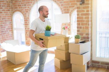 Genç yakışıklı adam yeni bir eve hareket, cardboxes SMIL tutarak