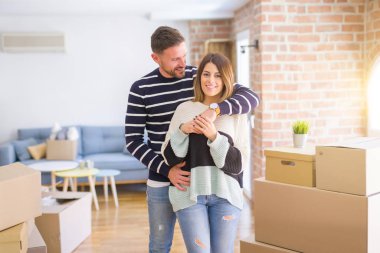 Karton kutular etrafında yeni evde sarılma genç güzel çift