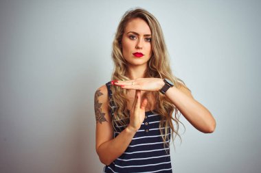 Çizgili tişört giyen genç ve güzel bir kadın beyaz tenli arka planda duruyor. Elleriyle, hayal kırıklığına uğramış ve ciddi bir yüz ifadesiyle jest yapıyor.