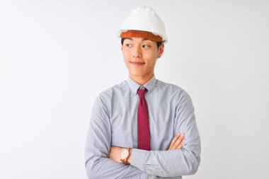 Çinli mimar kravat ve miğfer takıyor. İzole edilmiş beyaz arka planda duruyor. Gülümsüyor ve diğer tarafa bakıyor..