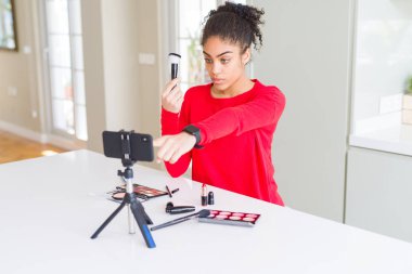 Genç afro-amerikan influencer kadın kayıt kamera ve size parmak ile işaret öğretici makyaj, el işareti, önden olumlu ve kendinden emin jest