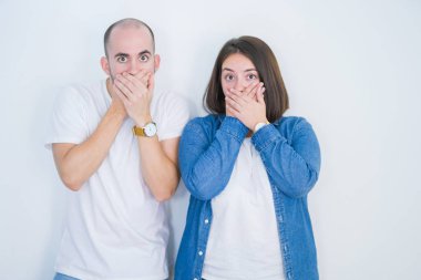 Beyaz arka planda genç bir çift, yanlışlıkla ağızlarını kapatarak şok geçirdiler. Gizli konsept.