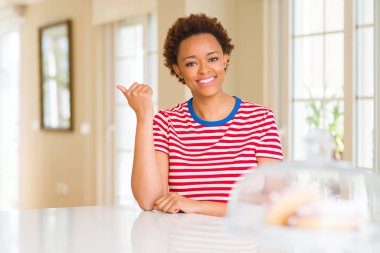 Gülümseyen genç güzel Afrikalı-Amerikalı kadın evde seyir ve başparmak yanında yukarıyı mutlu yüz.