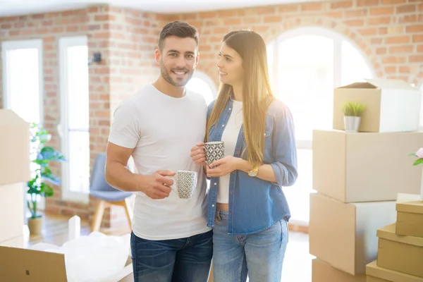 Hermosa pareja mudándose a una nueva casa, sonriendo alegre drinkin — Foto de Stock