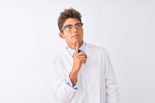 Young handsome sciencist man wearing glasses and coat over isolated white background Thinking concentrated about doubt with finger on chin and looking up wondering