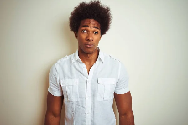 African american man with afro hair wearing shirt standing over isolated white background with serious expression on face. Simple and natural looking at the camera.