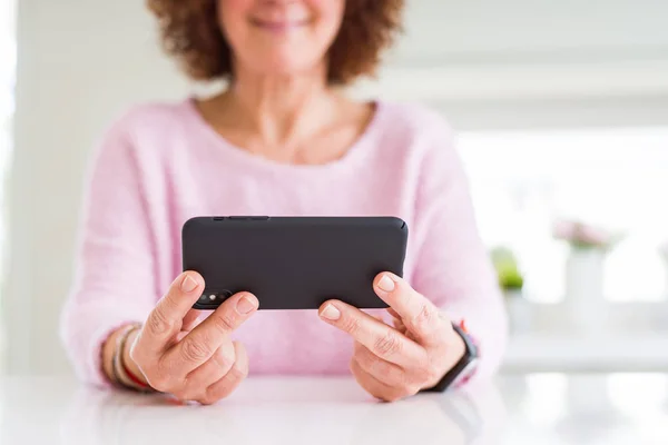 Primo piano di donna anziana utilizzando smartphone sopra tavolo bianco smili — Foto Stock
