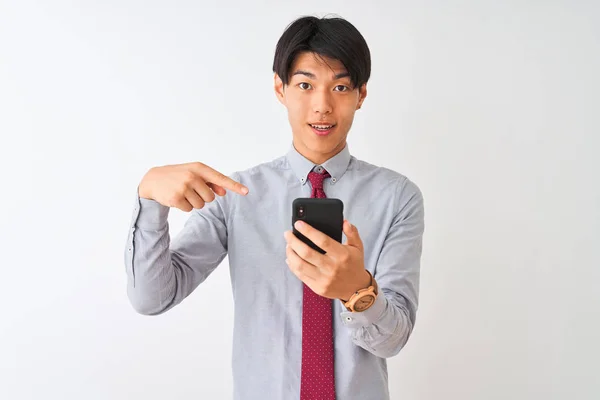 中国商人打着领带 用智能手机站在孤立的白色背景上 非常高兴地用手和手指指指点点 — 图库照片