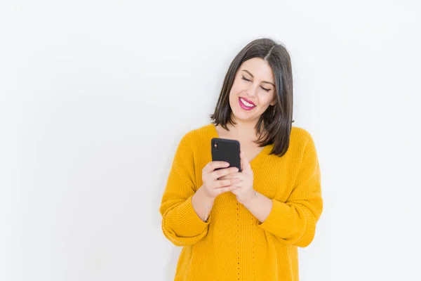 Schöne brünette junge Frau lächelt selbstbewusst mit Smartphone — Stockfoto
