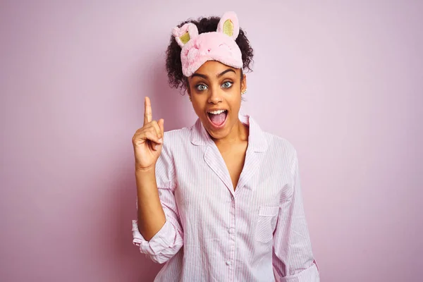 年轻的非洲裔美国女人 戴着睡衣和面罩 披着孤立的粉色背景 用手指指尖着成功的点子 又兴奋又快乐 第一部分 — 图库照片