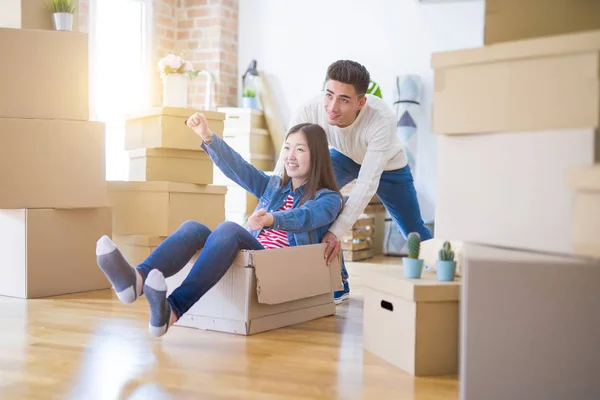 Divertida pareja asiática divirtiéndose, cabalgando dentro de la caja de cartón smili — Foto de Stock