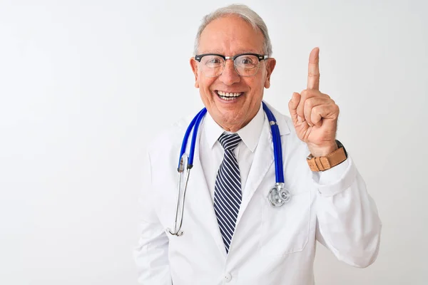 成功したアイデアで指を指す隔離された白い背景の上に立って聴診器を身に着けているシニア白髪の医師の男 興奮し 第一番 — ストック写真