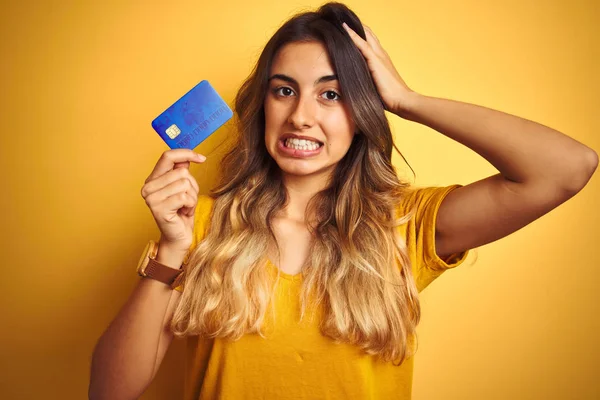 Młoda Piękna Kobieta Trzymająca Kartę Kredytową Żółtym Odizolowanym Tle Zestresowana — Zdjęcie stockowe