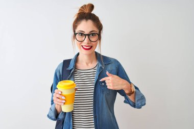 Güzel kızıl saçlı bayan kahve içerken izole edilmiş beyaz arka planda kendini gösteren sürpriz yüzlü.