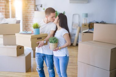 Young beautiful couple sitting on the floor at new home around cardboard boxes skeptic and nervous, disapproving expression on face with crossed arms. Negative person.