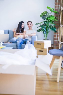 Genç güzel çift karton kutular etrafında yeni evde kahve içme kanepede oturan
