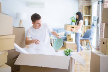 Young beautiful couple sitting on the floor at new home around cardboard boxes skeptic and nervous, disapproving expression on face with crossed arms. Negative person.