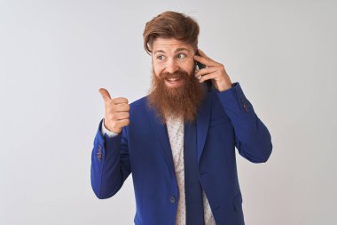 Genç kızıl saçlı İrlandalı işadamı, izole edilmiş beyaz arka plan üzerinden konuşuyor ve gülümseyen bir yüzle baş parmağıyla onu işaret ediyor.