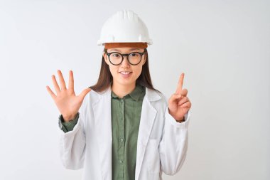 Genç Çinli mühendis kadın gözlük takıyor. İzole edilmiş beyaz arka planı var. Altıncı parmaklarıyla işaret ederken kendinden emin ve mutlu gülümsüyor..