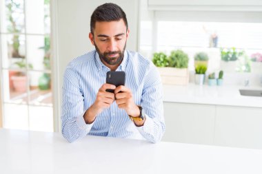 Yakışıklı bir İspanyol iş adamı akıllı telefon kullanıyor. Akıllı bir yüz ifadesi var ve ciddi düşünüyor.