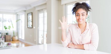 Afro saçlı güzel Afro-Amerikan kadının geniş açılı görüntüsü beş numarayı gösterirken kendine güvenen ve mutlu gülümseyen..