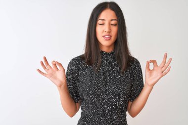 Soyutlanmış beyaz arka planda duran zarif tişört giyen genç Çinli kadın rahatla ve gözleri kapalı meditasyon hareketi yaparken parmaklarınla gülümse. Yoga konsepti.