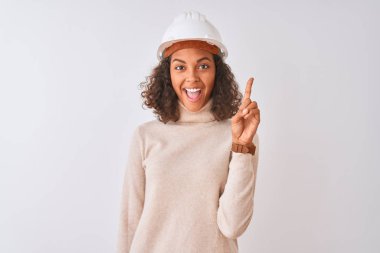 İzole edilmiş beyaz arka plan üzerinde güvenlik kaskı takan genç Brezilyalı mimar kadın başarılı bir fikir işaret ediyor. Heyecanlı ve mutlu. Bir numara..