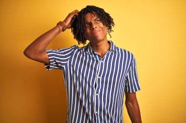 Rastgele çizgili tişört giyen Afro bir adam izole edilmiş sarı arka plan kafa karıştırıcı ve soru hakkında merak uyandırıcı. Şüpheyle kararsız, kafa kafaya düşünerek. Düşünceli kavram.