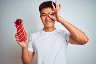 Sevgililer günü kartı tutan Asyalı genç adam mutlu yüzüyle izole edilmiş beyaz arka planda duruyor.