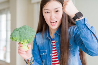 Yeşil taze brokoli yemek güzel Asyalı kadın rahatsız ve boşa çıkarmak ile öfke, çılgın da yükseltilmiş el ile bağırmaya kavramı öfke