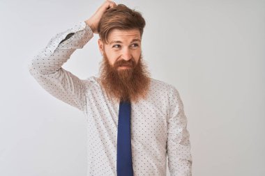 Genç kızıl saçlı İrlandalı işadamı izole edilmiş beyaz arka planda duruyor. Kafası karışıyor ve soru soruyor. Şüpheyle kararsız, kafa kafaya düşünerek. Düşünceli kavram.