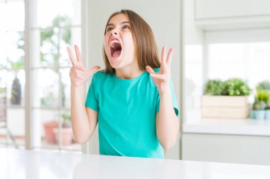 Yeşil tişört giyen genç ve güzel bir kız. Deli gibi bağırıyor, agresif bir ifadeyle bağırıyor ve kollarını kaldırıyor. Hayal kırıklığı konsepti.