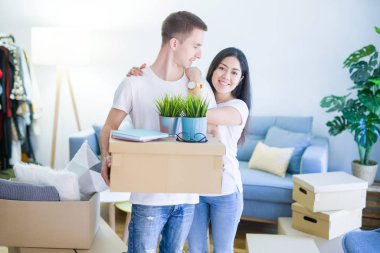Young beautiful couple sitting on the floor at new home around cardboard boxes skeptic and nervous, disapproving expression on face with crossed arms. Negative person.