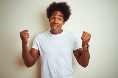 Afro saçlı Afrikalı bir adam izole edilmiş beyaz arka planda dikilmiş gururla bağırıyor ve zaferi ve başarıyı kutluyor.