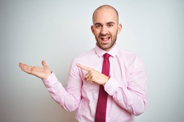 Soyutlanmış arka planda pembe kravat takan genç iş adamı kameraya hayret ediyor ve gülümsüyor..