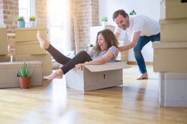 Orta yaş üst düzey romantik çift, eğlenceli karton içinde sürme, heyecanlı ve yeni bir eve taşımak için mutlu gülümseyen