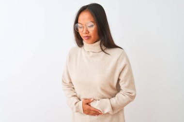 Balıkçı yaka kazak ve gözlük takan genç Çinli bir kadın, midesi ağrıyan, hazımsızlık çeken, ağrılı bir hastalık yüzünden izole edilmiş beyaz arka plan üzerine. Ache kavramı.