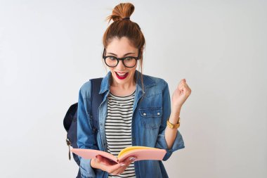 Sırt çantası takan kızıl saçlı kadın izole edilmiş beyaz arka planda kitap okuyor. Gururla bağırıyor, zaferi kutluyor ve başarıyı kutluyor. Çok heyecanlı, neşeli bir duygu.