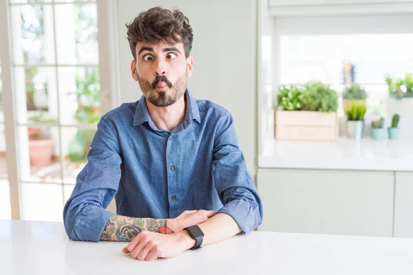 Hombre Joven Con Camisa Casual Sentado Mesa Blanca Haciendo Cara — Foto de Stock