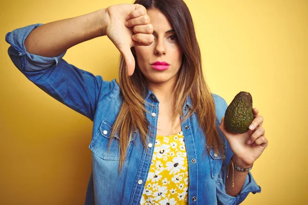 Young Beautiful Woman Eating Healthy Avocado Yellow Background Angry Face — Stock Photo, Image