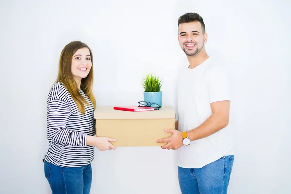 Jovem lindo casal segurando caixa de papelão sobre isolado branco — Fotografia de Stock