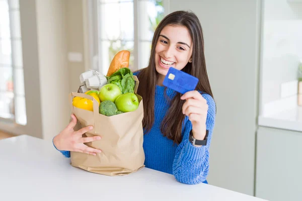 Молода жінка тримає паперовий пакет, повний свіжих продуктів і шоу — стокове фото